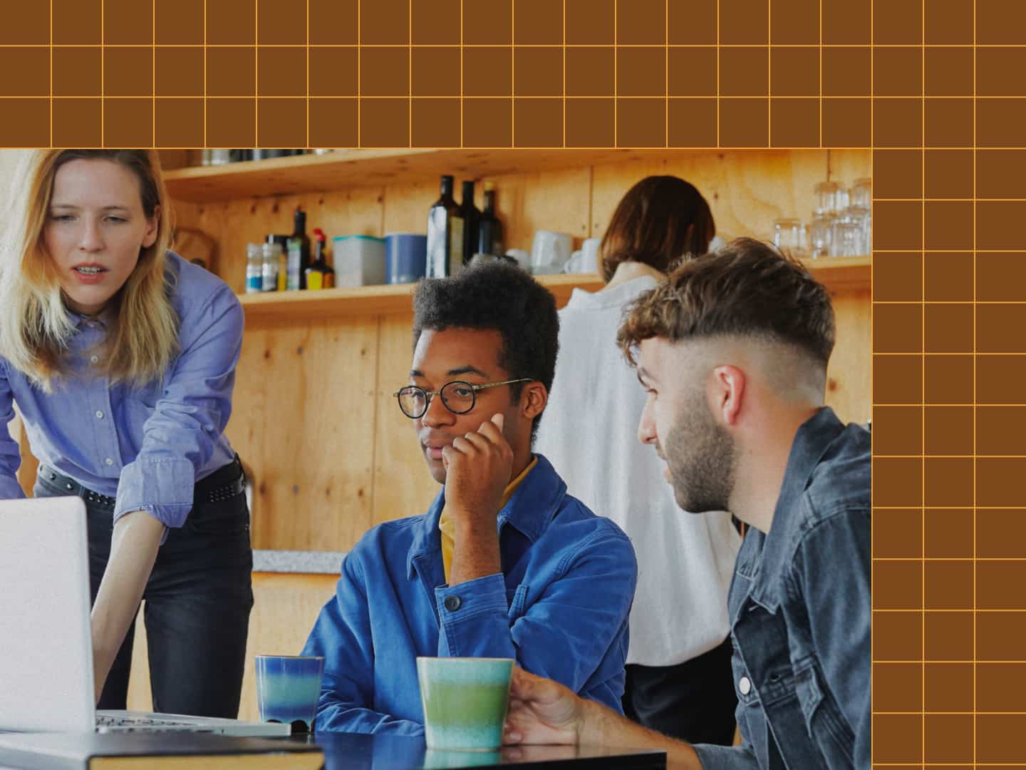 Three individuals sit by a laptop, working at an agency.